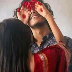 a man covering his eyes with both hands while standing next to a woman's head