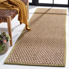 a large rug in the middle of a room next to a chair and potted plant