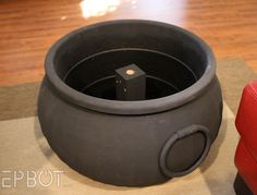 a large black pot sitting on top of a wooden floor next to a red chair