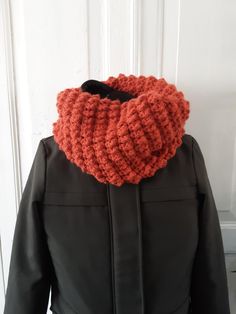 an orange knitted scarf hanging from the back of a jacket