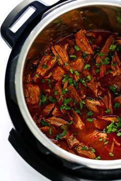 a large pot filled with meat and garnish on top of a white table