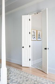 an open door leading to another room with pictures on the wall and rug in front of it