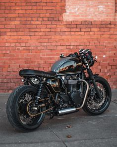 a black motorcycle parked in front of a brick wall