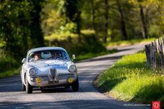 an old car driving down a country road