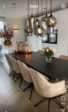 a dining room table with chairs and lights hanging from it's centerpieces