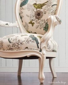 a white chair with floral upholstered back and arm rests on a wooden floor