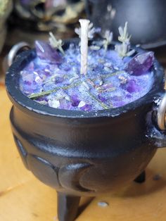 a black pot filled with purple flowers on top of a wooden table