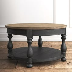 a round coffee table with two wooden legs and a wood top on a hard wood floor