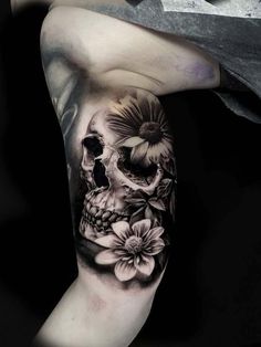 a man's arm with a skull and flowers on it