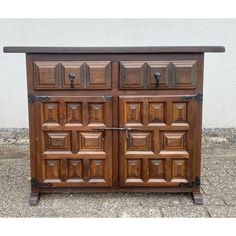 an old wooden cabinet with metal handles on the top and bottom, sitting in front of a wall