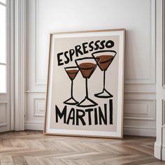 a framed poster with two martini glasses on the floor in front of a window that reads espresso martini