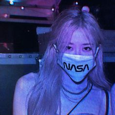 a woman wearing a face mask with the word nasa on it in front of her