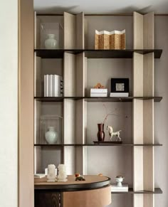 an empty room with shelves and vases on the wall, along with bookshelves