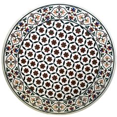 a white and black plate with red flowers on the bottom, surrounded by smaller circles