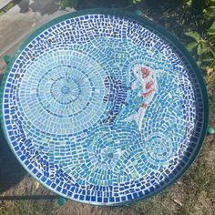 a blue and white mosaic table sitting in the grass