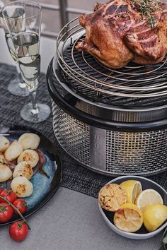 a table topped with plates of food next to a glass of water and a chicken on top of a grill