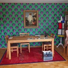 a table and chairs in front of a colorful wallpapered room with bookshelves