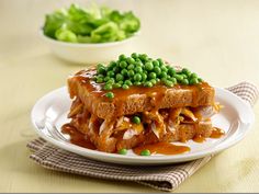 a plate topped with french toast covered in sauce and peas