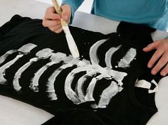 a person is painting a skeleton shirt with white paint