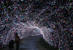 a person walking through a tunnel filled with lots of lights