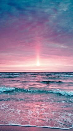 the sun is setting over the ocean with waves coming in to shore and pink sky