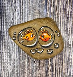 two goldfishs painted on top of rocks with water droplets and hearts around them