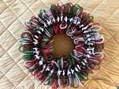 a red, white and green christmas wreath sitting on top of a bed