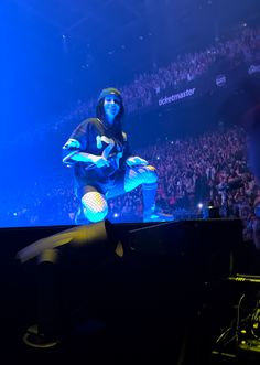 a man sitting on top of a piano in front of a crowd at a concert