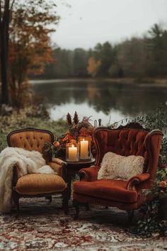 two chairs and a table with a candle on it in the middle of a field