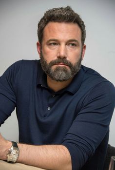 a man sitting at a table with his arms crossed and looking off to the side