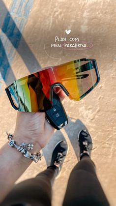 a person wearing sunglasses and bracelets holding up a cell phone to take a photo