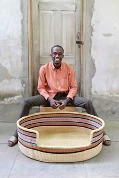 a man sitting in front of a door with a basket on the floor next to him