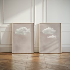 two framed pictures sitting on top of a hard wood floor next to a white wall