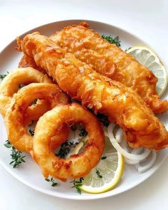 fried fish and onion rings on a plate with lemon wedges