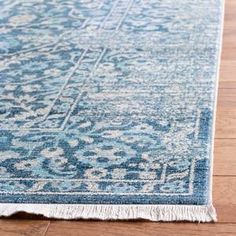 a blue and white rug with fringes on the bottom is laying on a wooden floor