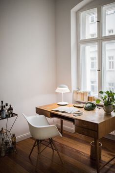 a room with a desk, chair and large window