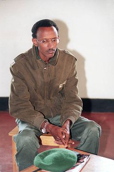 a man sitting on top of a wooden table next to a green hat in front of him