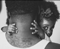 a black and white photo of a woman holding a child on her back with another person in the background