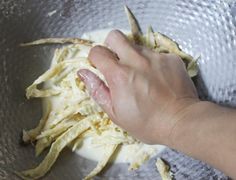 a person is kneading some food in a silver bowl on the table and it looks like they are peeling