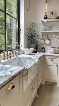 a kitchen with marble counter tops and gold faucets on the windowsills