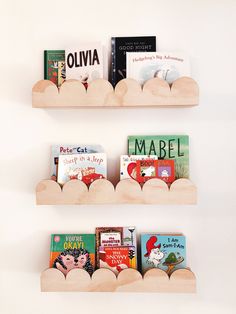 three wooden bookshelves with children's books on them in the shape of clouds