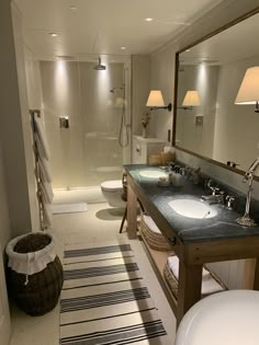 a bathroom with two sinks and a large mirror over the bathtub, along with a rug on the floor