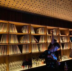 two men standing next to each other in front of shelves filled with records and drinks