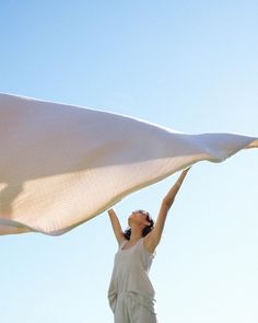 a woman holding up a white cloth in the air