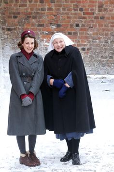 two women standing next to each other in the snow wearing coats and mittenss