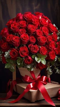 a bouquet of red roses in a wooden box with a ribbon around the bow on a table