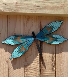 a blue dragonfly is mounted on a wooden fence, with the caption above it