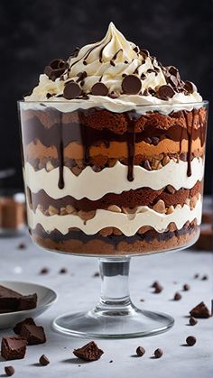 a cake with chocolate and cream frosting on top sitting in a glass trifle