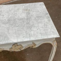 a white marble table with gold trimmings on the top and bottom, sitting in a room