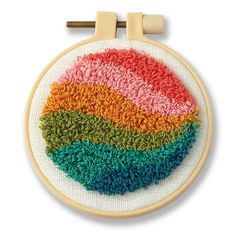 an embroidered rainbow circle on a wooden hoop